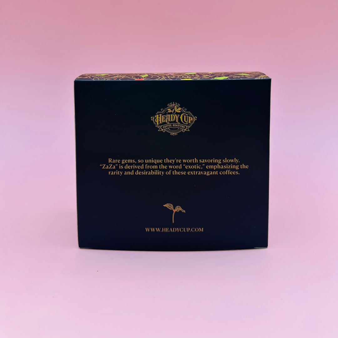 A black rectangular Heady Cup Coffee Roasters coffee box from their Zaza Collection, labeled 'Rare Gems', set against a solid pink background.