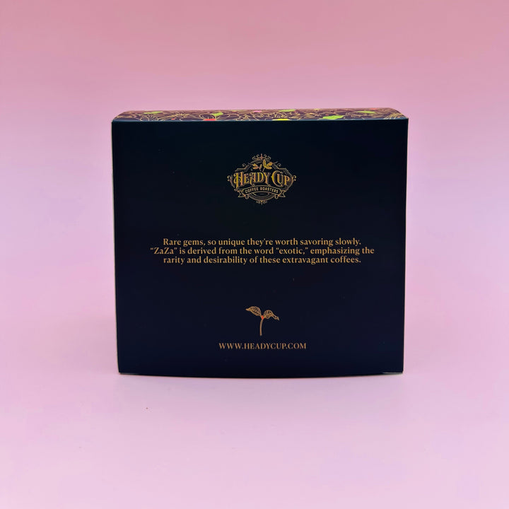 A black rectangular Heady Cup Coffee Roasters coffee box from their Zaza Collection, labeled 'Rare Gems', set against a solid pink background.