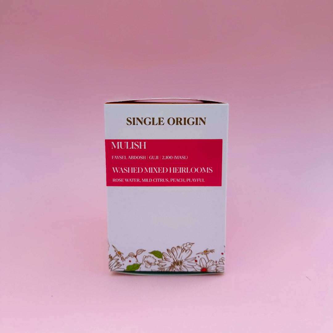 A rectangular box of Heady Cup Coffee Roasters single-origin Ethiopia Mulish Washed, featuring a white and red design with floral illustrations at the bottom, set against a solid pink background.