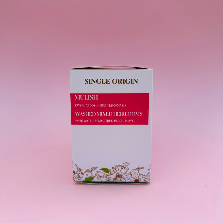 A rectangular box of Heady Cup Coffee Roasters single-origin Ethiopia Mulish Washed, featuring a white and red design with floral illustrations at the bottom, set against a solid pink background.