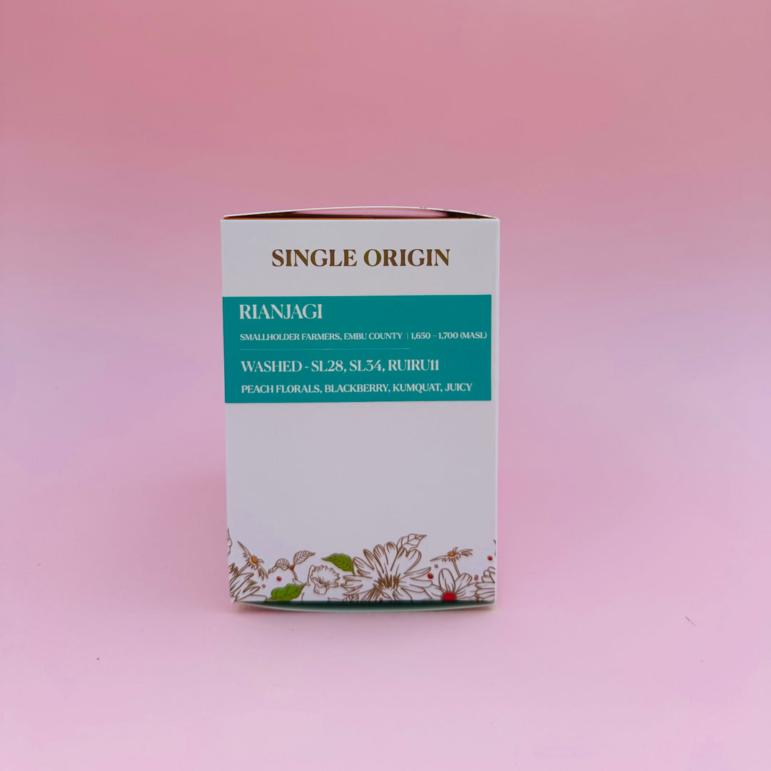 A rectangular white Heady Cup Coffee Roasters single-origin box with Rianjagi washed, featuring a teal label and floral illustrations at the bottom, set against a solid pink background.
