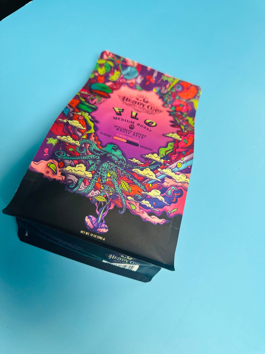 A colorful bag of Heady Cup Coffee Roasters medium roast coffee named Flo. A blue octopus on the front of the bag on a blue background. 